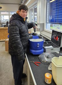 Ein Mitarbeiter schraubt einen Nasssauger auseinander.