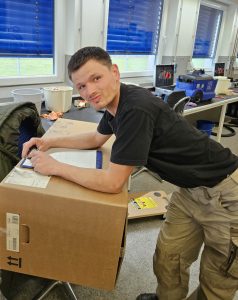 Ein Mitarbeiter kontrolliert einen Karton und schreibt Daten auf.