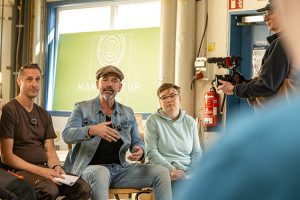 Schreiner und Betreuer Simon (v.l.) hatte Doc Esser mit einem Video eingeladen, das er zusammen mit der Beschäftigten im Saunabau Jasmin aufgenommen hatte. Bild: Tameer Gunnar Eden/Eifeler Presse Agentur/epa