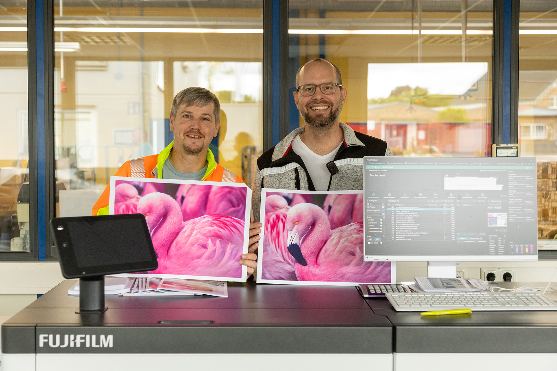 Betriebsleiter Andreas Winkelhag (l.) und Philipp Bungenberg vom Druckzentrum stellen die neue Druckmaschine vor. Die kann durch die Sonderfarbe Pink gerade die Farben Rot, Rosa und Orange besser drucken. Foto: Tameer Eden