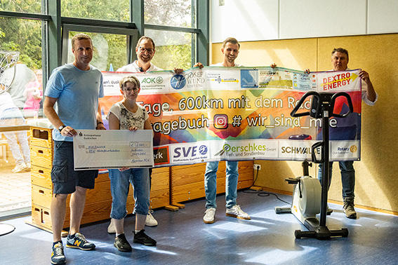 Starker Einsatz: Sportlehrer Carsten Heuser (v.l.) übergibt den Scheck an Katharina Ziolkowska, Vorsitzende Behindertensportgemeinschaft der NE.W, und NE.W-Geschäftsführer Christoph Werner. Wie Sportlehrer Kai Ries und Schulleiter Michael Mombauer berichteten, war das Geld durch eine Alpen-Radtour zusammengekommen. Bild: Tameer Gunnar Eden/Eifeler Presse Agentur/epa